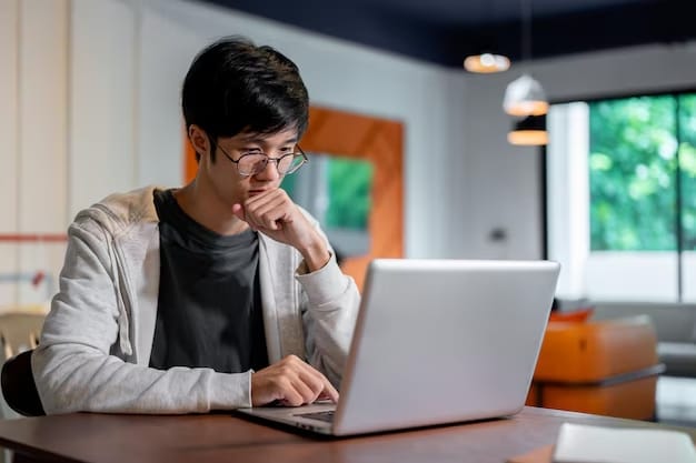 jovem asiatico lendo matérias em seu laptop e consumindo conteúdo de outbrain ads por tráfego pago