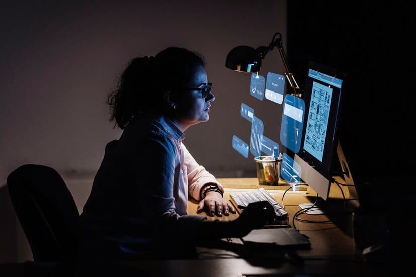empresária em sua casa no escuro análisando gráficos sobre seu negócio e pensando em melhoria de performance com monitoramento de E-Commerce
